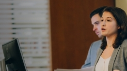 Two students in front of a computer screen in a classroom.