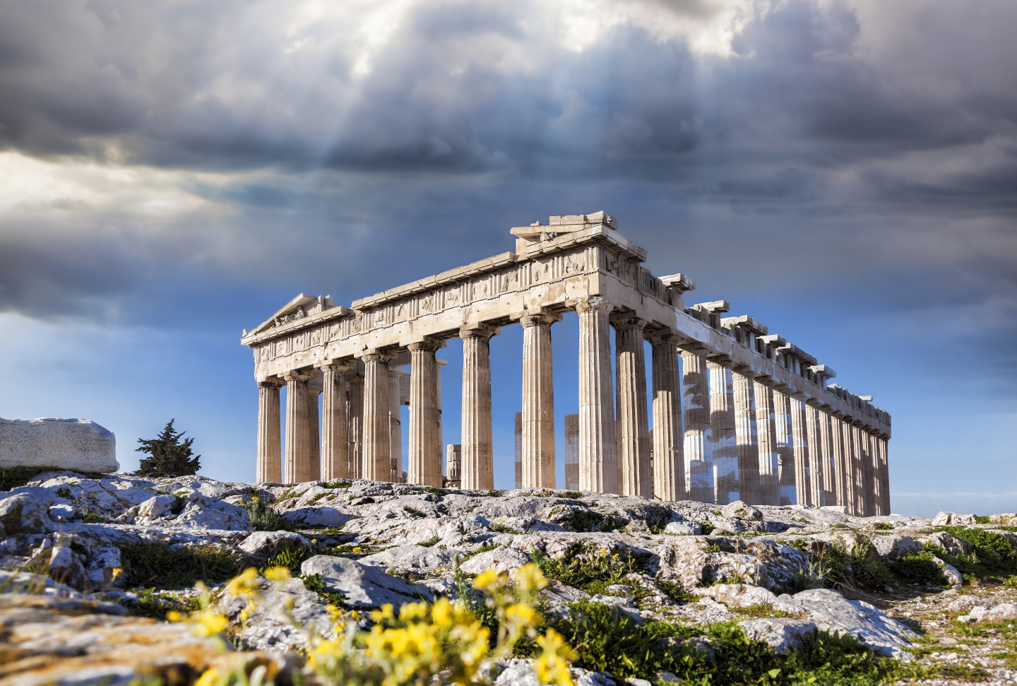 Sunlight peaks through storm clouds over the Acropolis in Athens, Greece