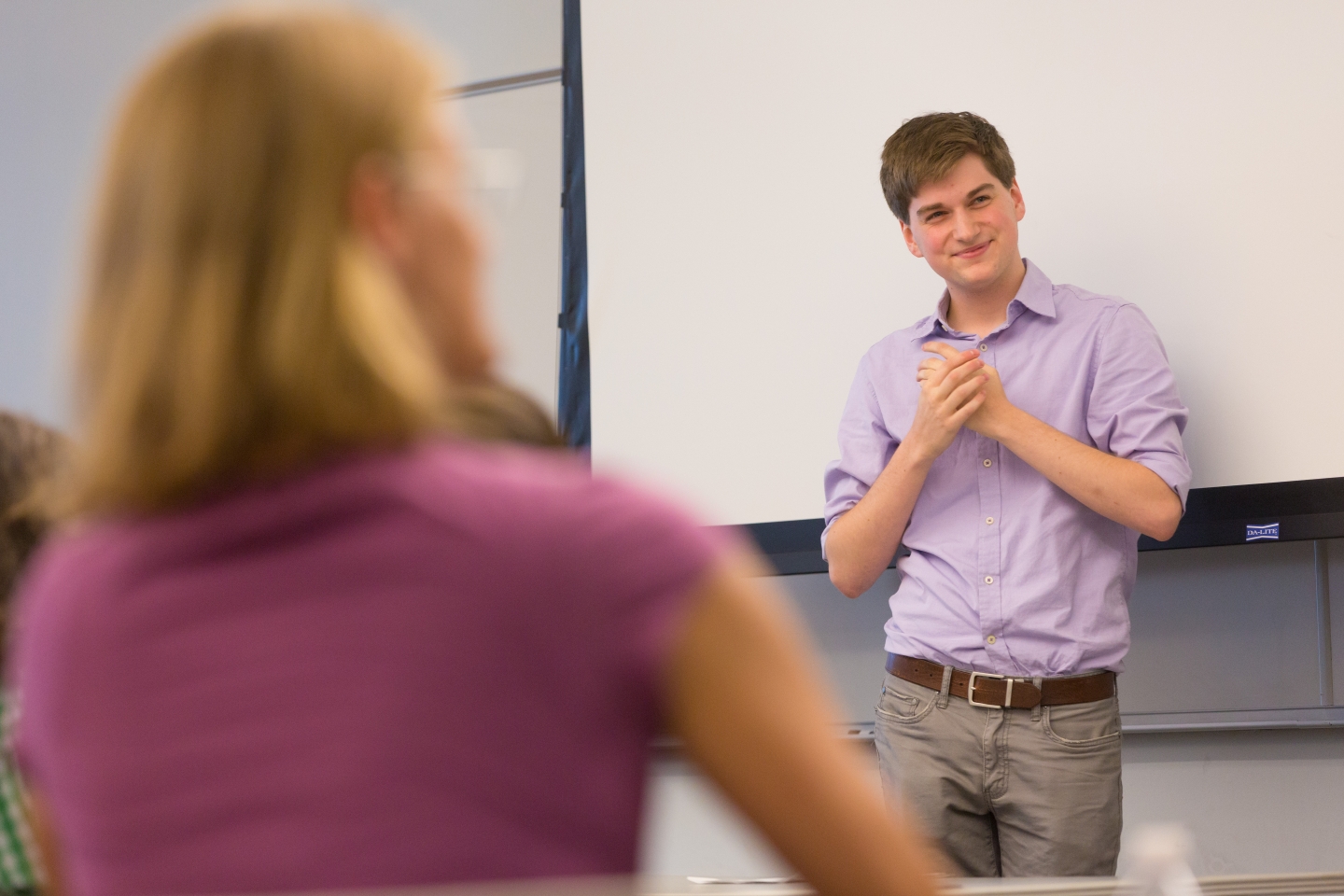 Professor smiles at the front of classroom.
