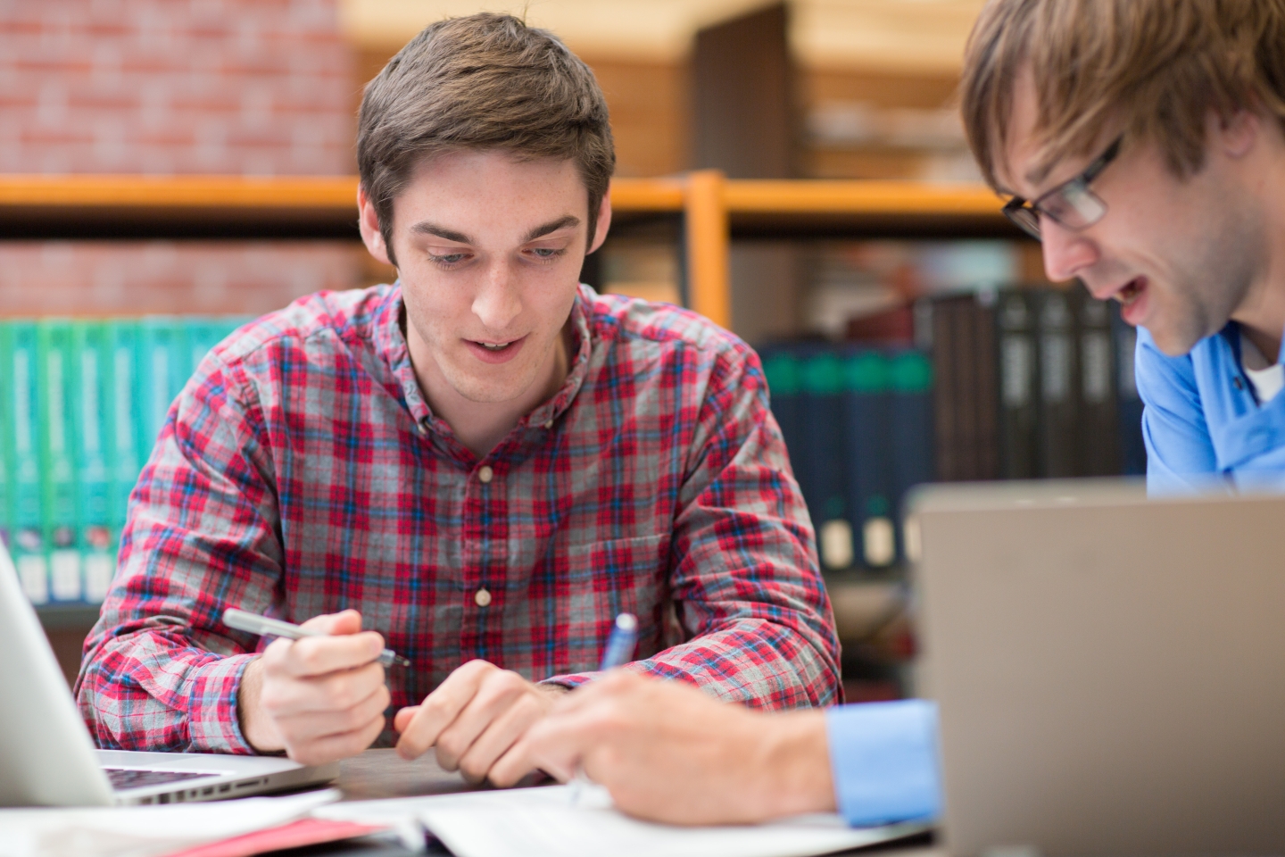 Two students discussing and writing in book