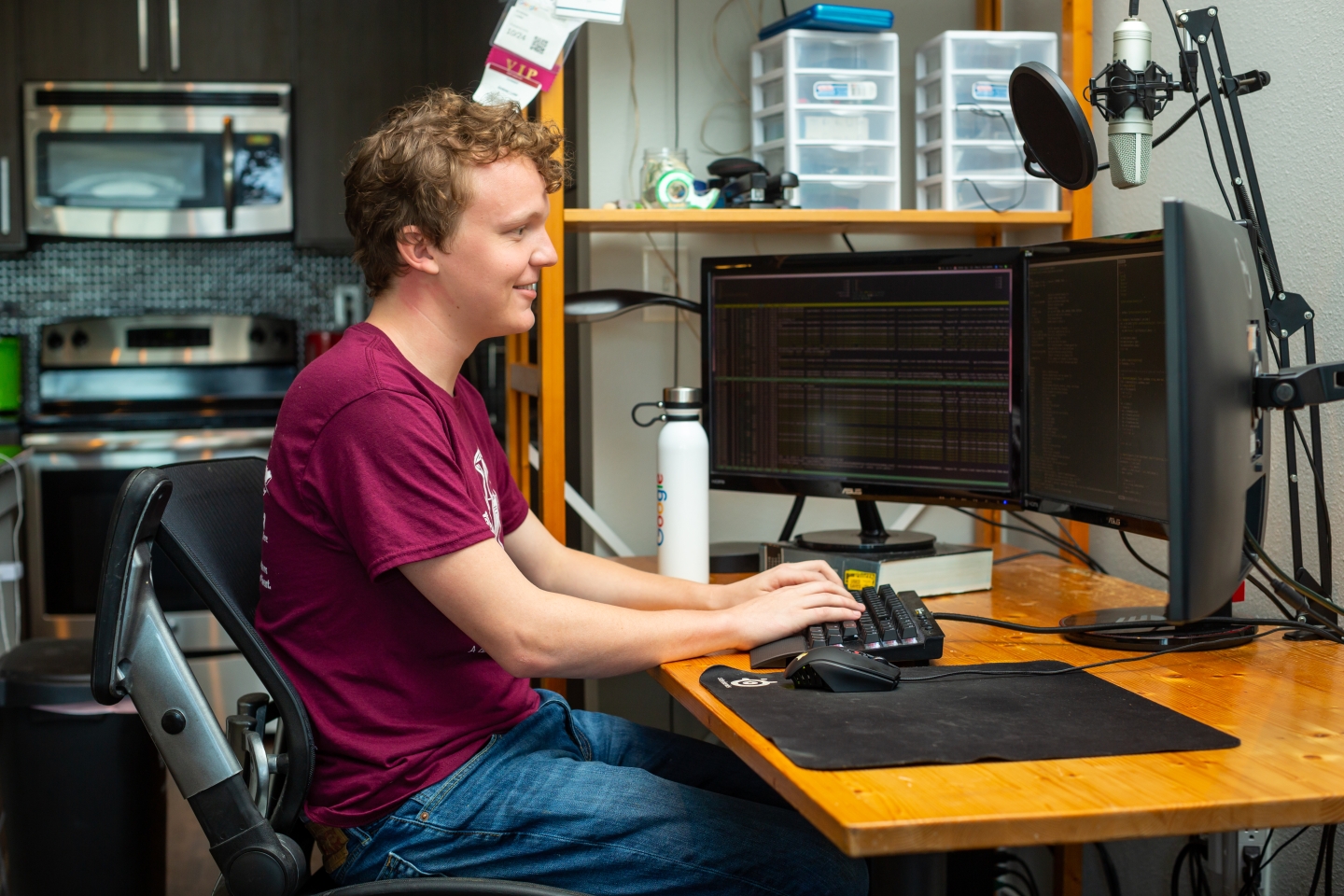 person sitting at desk in front of three computer screens