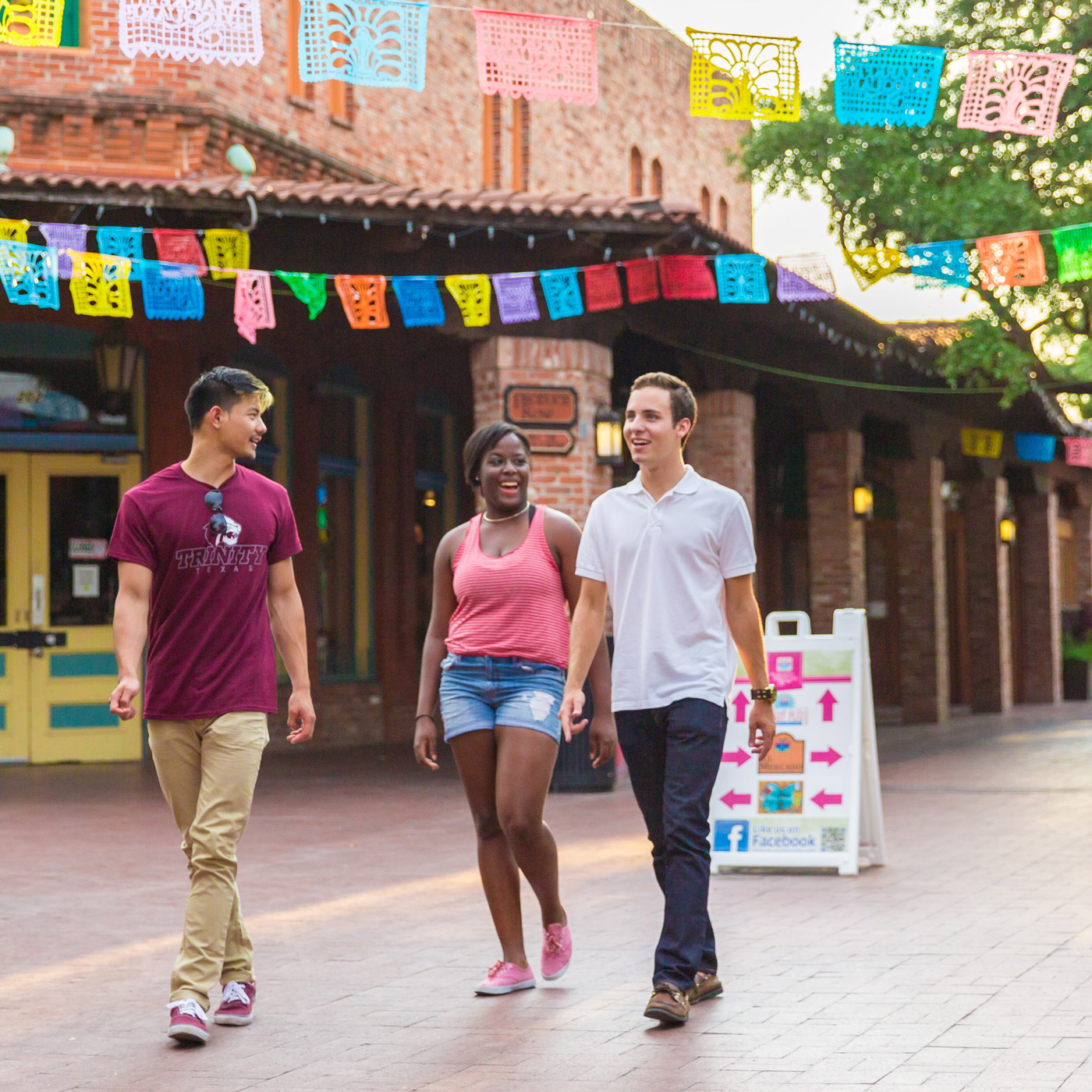 three Trinity students walk through Market Square under papel picado