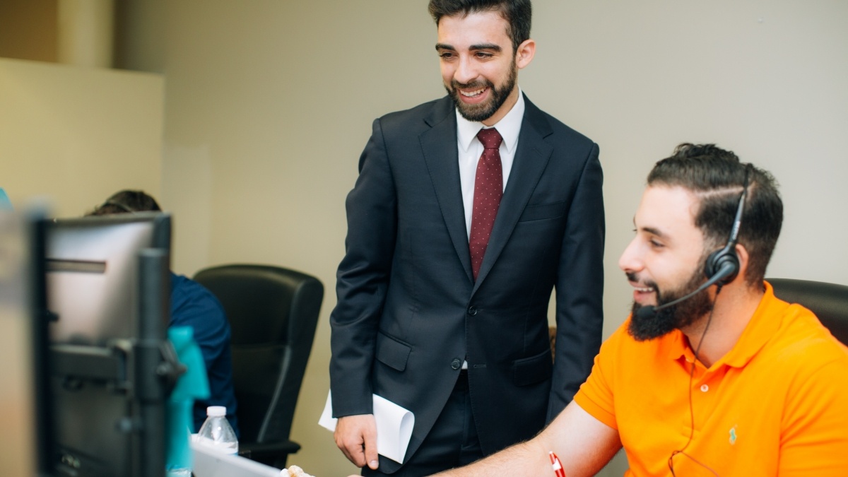 two students sitting while talking to one student standing