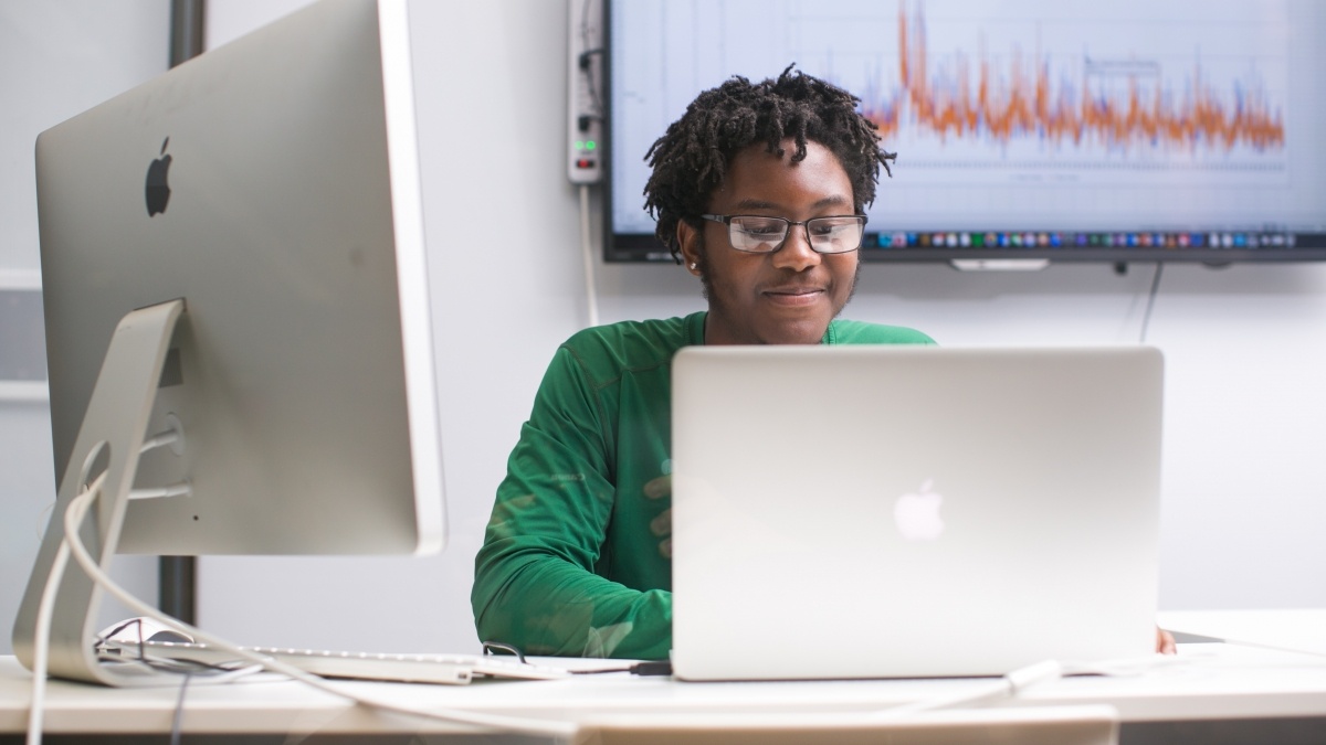 Student working on computer with two monitors