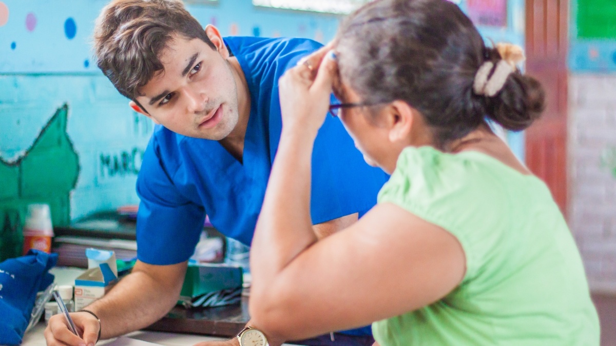 Doctor takes notes while speaking with a patient.
