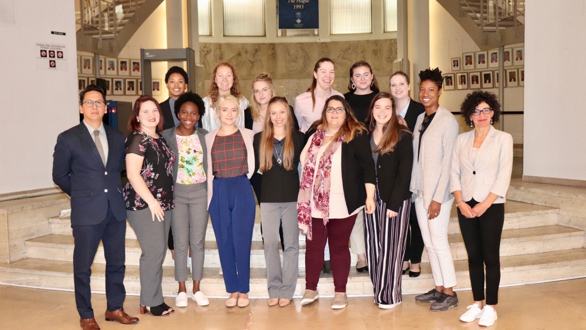 Student group poses in front of banner for The Hague.