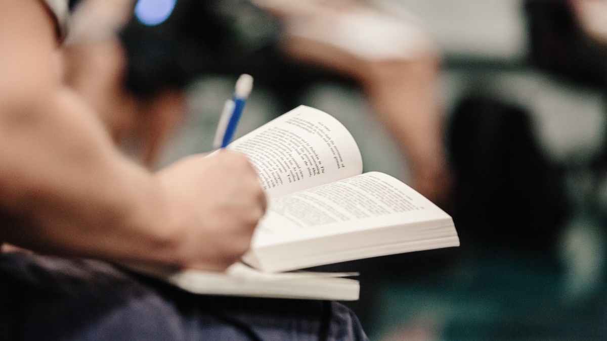 A student writes notes in an open book