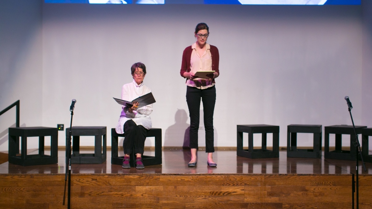Two students on stage hold their screenplay scripts