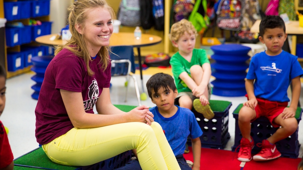 Trinity student talking to a group of elementary students