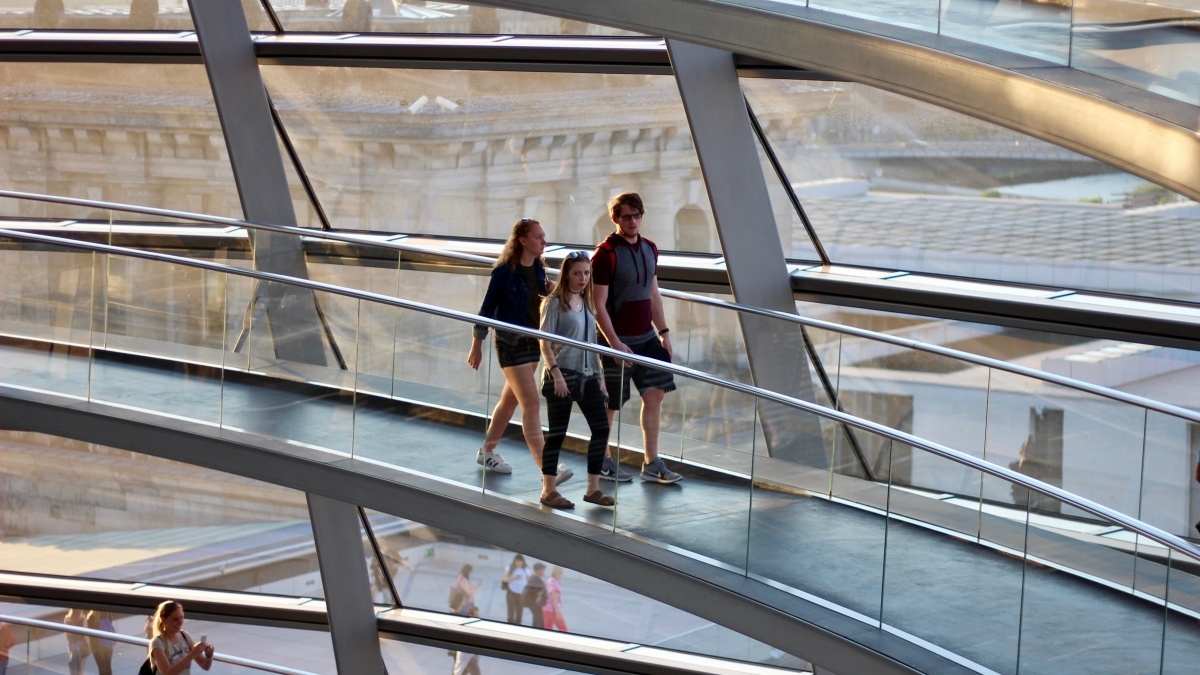 Students walking on indoor walkway with glass wall behind them
