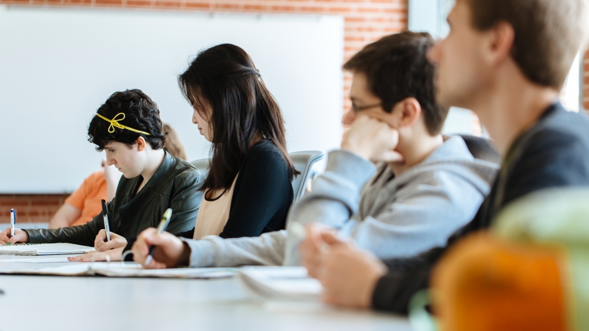 Students sitting at long table listening to lecture