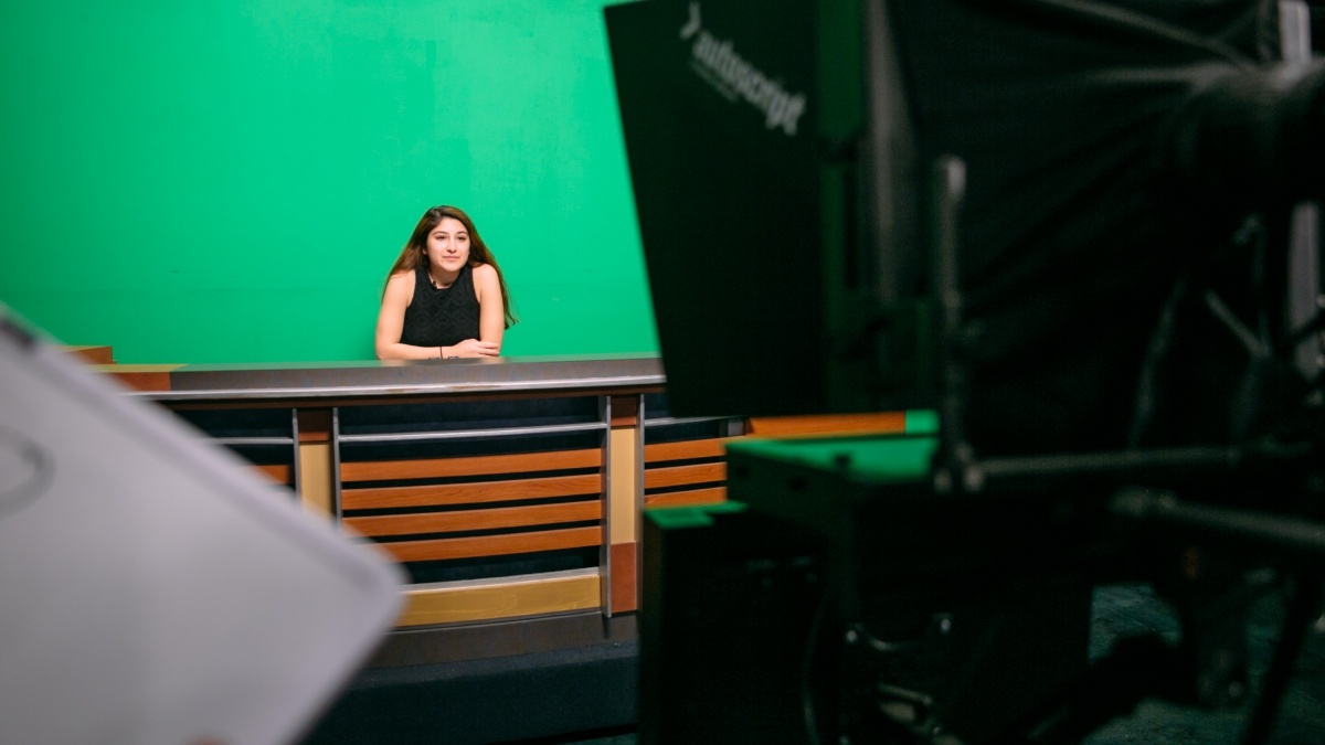 A student is filmed in front of a green screen for TigerTV