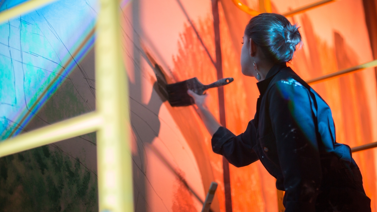 Woman painting mural on set.