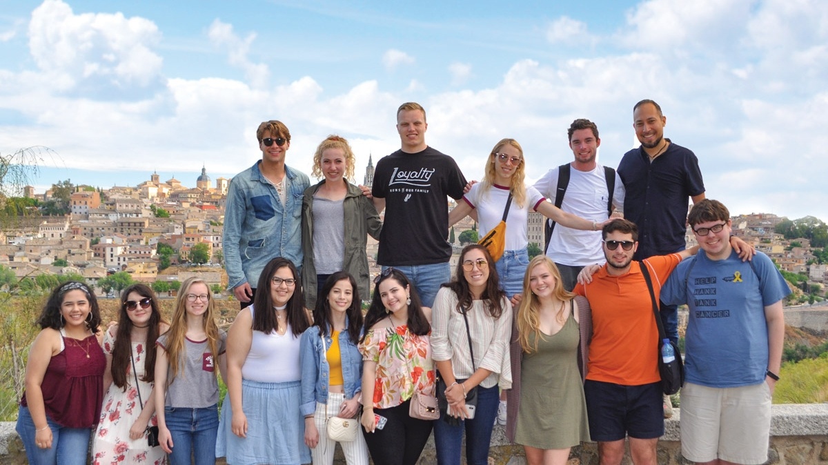 a group photo posed in front of the background of historic Madrid Spain
