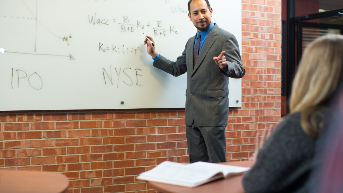 Professor at the whiteboard presenting to class.