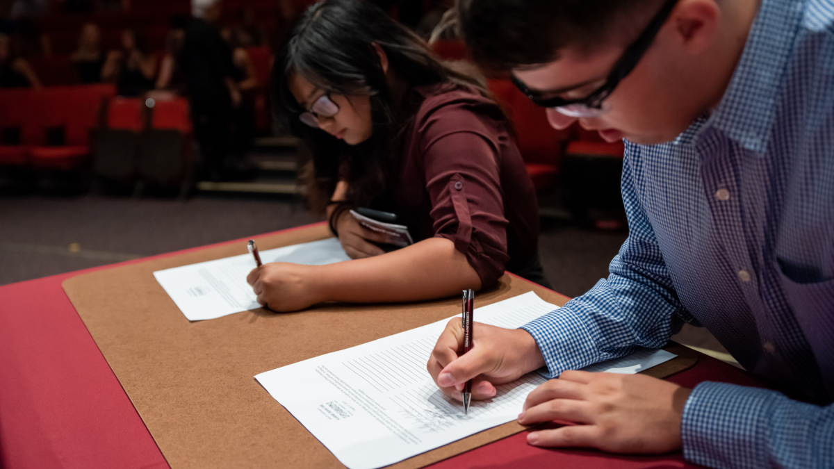 Two students signing the academic honor code