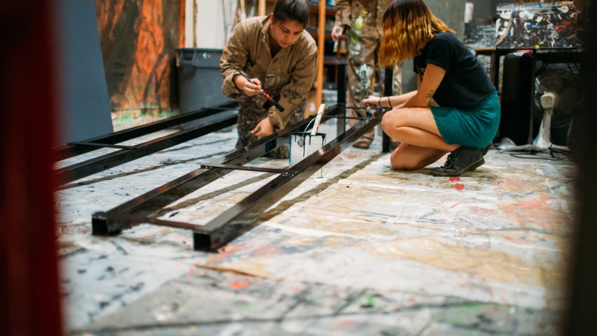 Two students in the paint studio painting for production