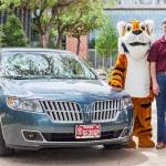 Dave and Carol Mansen and LeeRoy the Tiger pose by their car in front of CSI